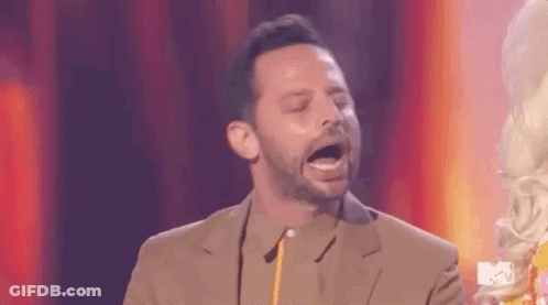 A Man In A Suit Is Standing On A Stage With His Mouth Open And Holding A Trophy . GIF