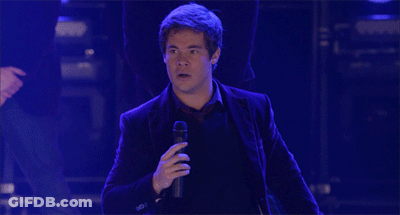 A Man In A Suit Is Standing With His Arms Outstretched GIF