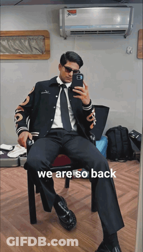A Man In A Suit Is Taking A Picture Of Himself With The Words We Are So Back Below Him GIF