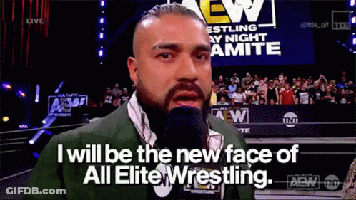 A Man In A Suit Is Talking Into A Microphone While Standing In Front Of A Crowd . GIF