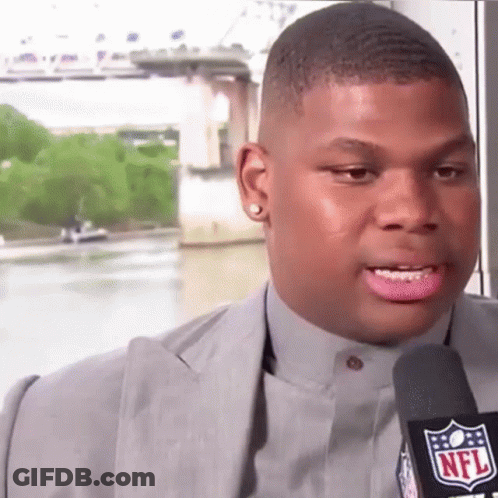 A Man In A Suit Is Talking Into A Microphone With The NFL Logo On It GIF