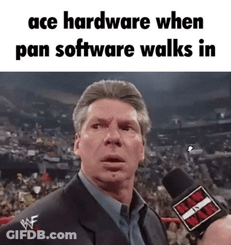 A Man In A Suit Is Talking Into A Microphone With The Words Ace Hardware When Pan Software Walks In . GIF