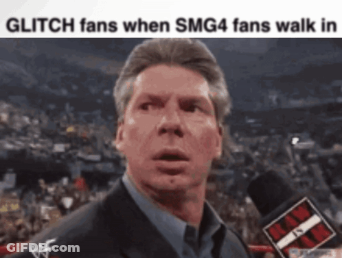 A Man In A Suit Is Talking Into A Microphone With The Words Glitch Fans When Smg4 Fans Walk In Below Him GIF