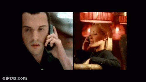 A Man In A Suit Is Talking On A Cell Phone Next To A Woman Sitting On A Couch Talking On A Cell Phone GIF