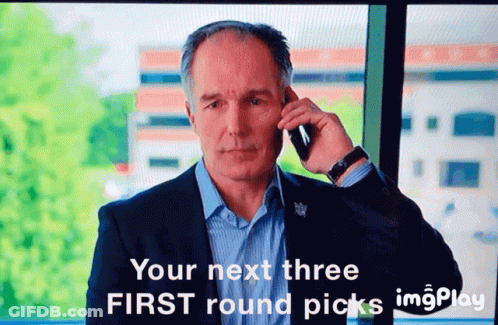 A Man In A Suit Is Talking On A Cell Phone With The Words " Your Next Three First Round Picks " Above Him GIF