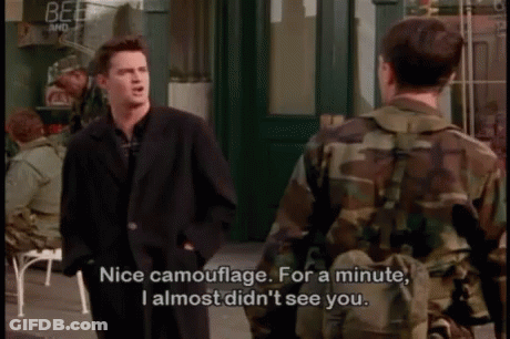 A Man In A Suit Is Talking To A Man In A Camo Jacket GIF