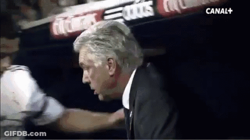 A Man In A Suit Is Talking To A Man In A White Shirt In A Dark Room . GIF