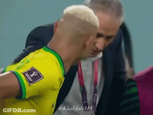 A Man In A Suit Is Talking To A Soccer Player Who Is Wearing A Yellow Shirt With The Number 1 On It . GIF