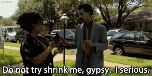 A Man In A Suit Is Talking To A Woman Who Is Holding A Gun And Says Do Not Try Shrink Me Gypsy GIF