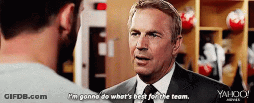 A Man In A Suit Is Talking To Another Man In A Locker Room . GIF