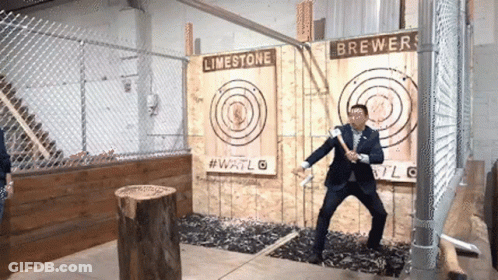 A Man In A Suit Is Throwing An Axe At A Target That Says Limestone Brewers On It GIF