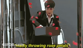 A Man In A Suit Is Throwing Rose Petals At The Camera GIF