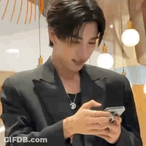 A Man In A Suit Is Using A Cell Phone . GIF