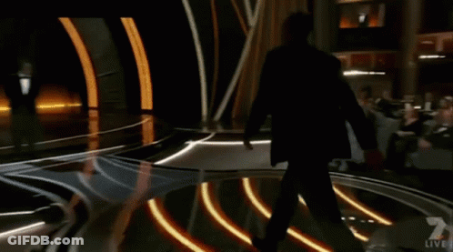 A Man In A Suit Is Walking Across A Stage With A Live Sign On It GIF