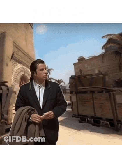 A Man In A Suit Is Walking Down A Desert Road GIF