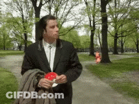 A Man In A Suit Is Walking Down A Path Holding A Lollipop GIF