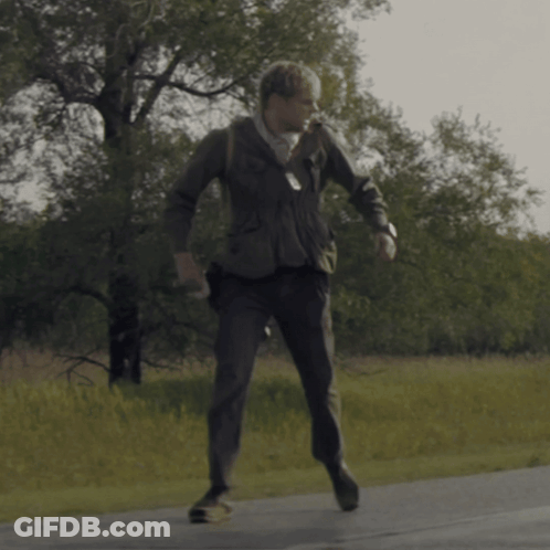 A Man In A Suit Is Walking Down A Street GIF
