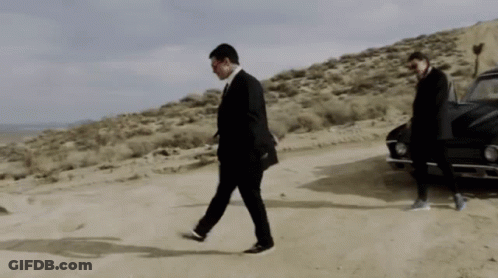 A Man In A Suit Is Walking In The Desert GIF