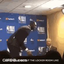 A Man In A Suit Is Walking Out Of A Locker Room Like A Basketball Player . GIF