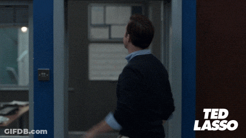 A Man In A Suit Is Waving At A Sign That Says " Believe " GIF