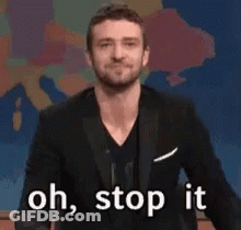 A Man In A Suit Is Waving His Hand And Saying Oh Stop It GIF
