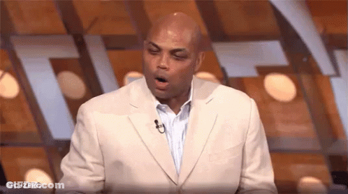 A Man In A Suit Is Yawning While Standing In Front Of A Microphone On A Stage . GIF