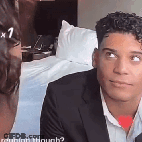 A Man In A Suit Looks At A Woman In A White Shirt . GIF