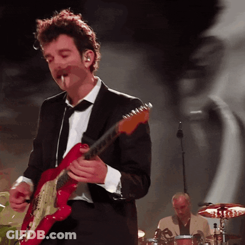 A Man In A Suit Plays A Red Guitar GIF
