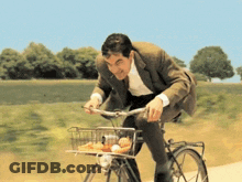 A Man In A Suit Rides A Bike With A Basket Full Of Food GIF