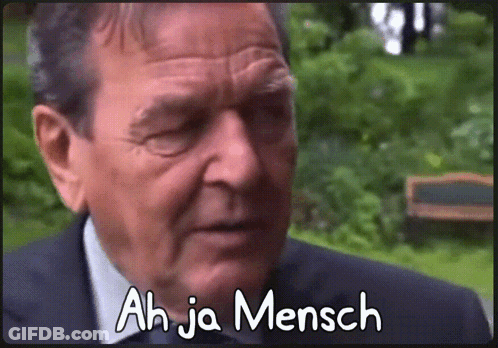A Man In A Suit Says Ah Ja Mensch On The Screen GIF