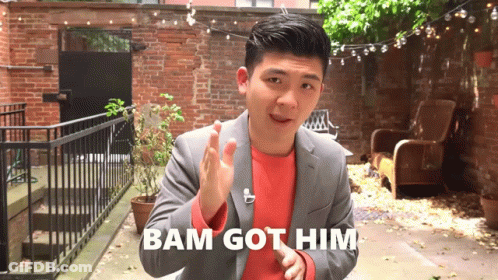 A Man In A Suit Says Bam Got Him While Standing In Front Of A Brick Wall GIF