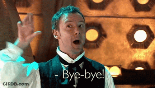 A Man In A Suit Says Bye-Bye In A Dark Room GIF