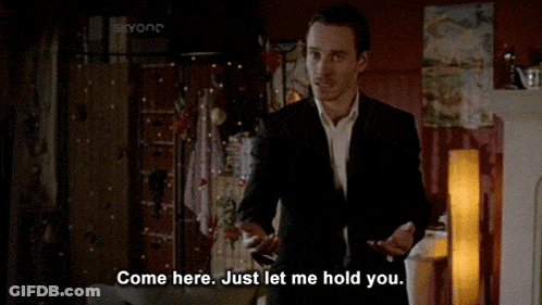 A Man In A Suit Says Come Here Just Let Me Hold You In A Living Room GIF