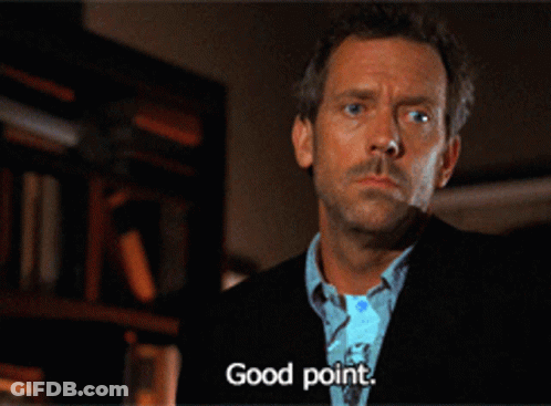 A Man In A Suit Says " Good Point " In Front Of A Bookshelf GIF
