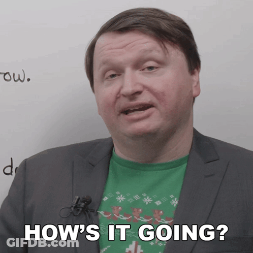 A Man In A Suit Says How 'S It Going In Front Of A White Board GIF