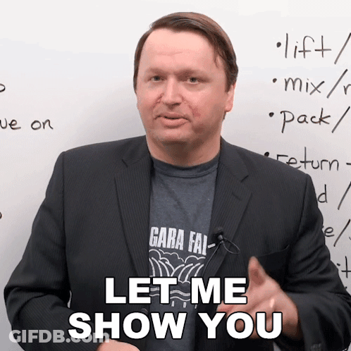 A Man In A Suit Says " Let Me Show You " In Front Of A White Board GIF