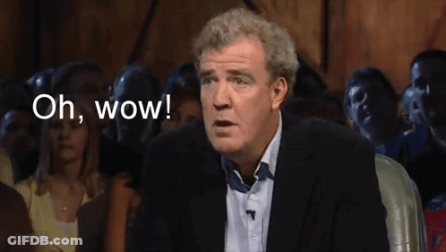 A Man In A Suit Says " Oh Wow " In Front Of A Crowd Of People GIF
