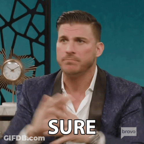 A Man In A Suit Says Sure In Front Of A Bravo Logo GIF