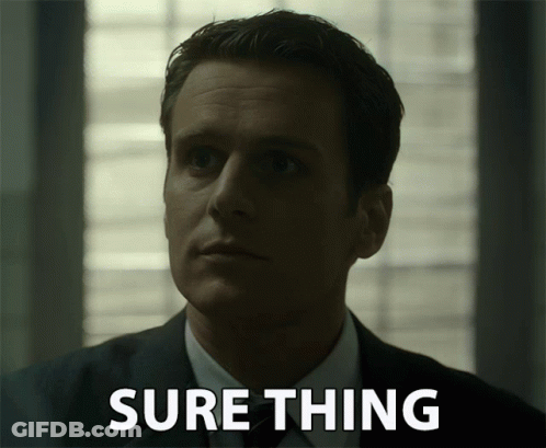 A Man In A Suit Says Sure Thing In Front Of Him GIF