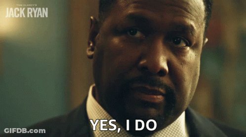 A Man In A Suit Says Yes I Do In Front Of A Poster For Jack Ryan GIF