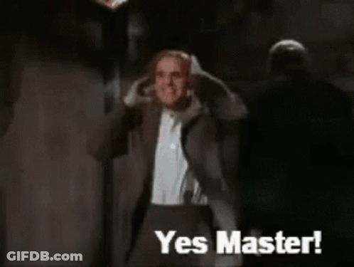 A Man In A Suit Says Yes Master In Front Of A Monster GIF