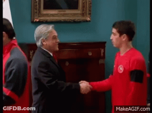 A Man In A Suit Shaking Hands With A Man In A Red Shirt GIF