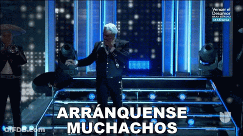 A Man In A Suit Singing Into A Microphone With Arranquense Muchachos Written Below Him GIF
