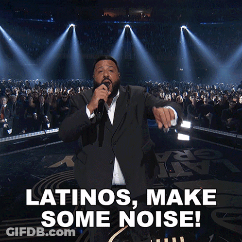 A Man In A Suit Singing Into A Microphone With The Words Latinos Make Some Noise Below Him GIF