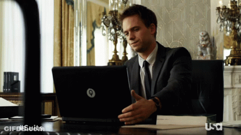 A Man In A Suit Sits At A Desk With A Laptop And A Usa Logo GIF