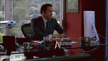 A Man In A Suit Sits At A Desk With A Sign On It That Says Immunity GIF
