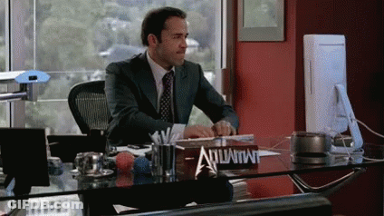 A Man In A Suit Sits At A Desk With A Sign That Says Advantage On It GIF
