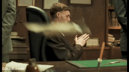 A Man In A Suit Sits At A Desk With His Hands Folded In Front Of Him GIF