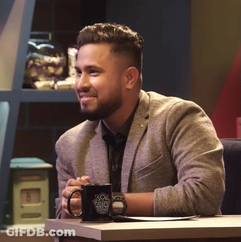 A Man In A Suit Sits At A Table With A Coffee Mug That Says ' Son Of A Bitch ' On It GIF