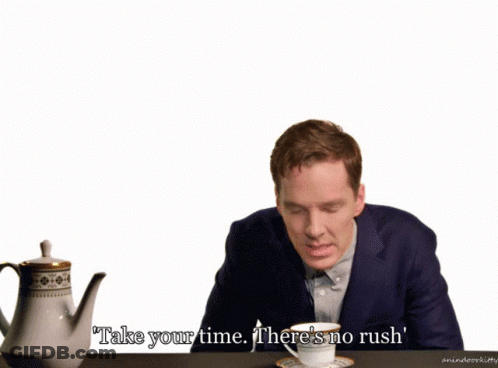 A Man In A Suit Sits At A Table With A Cup Of Tea And Says Take Your Time There 'S No Rush ' GIF